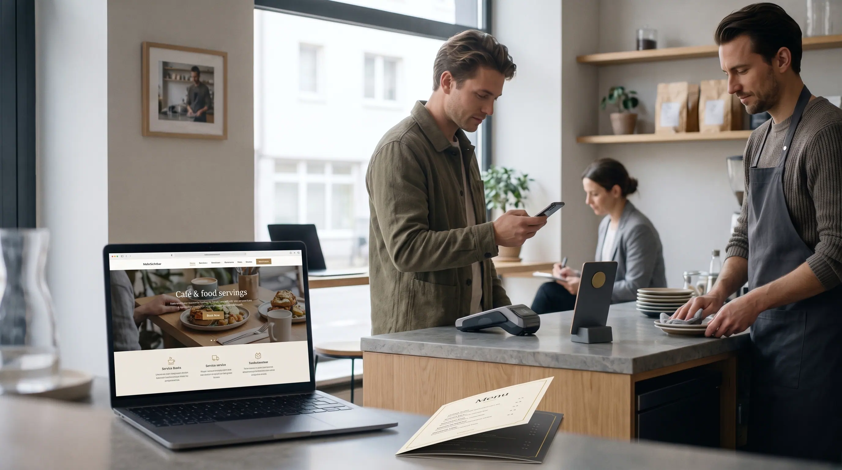 Gast im Café mit Smartphone, daneben die Website auf dem Laptop und eine gedruckte Menükarte.