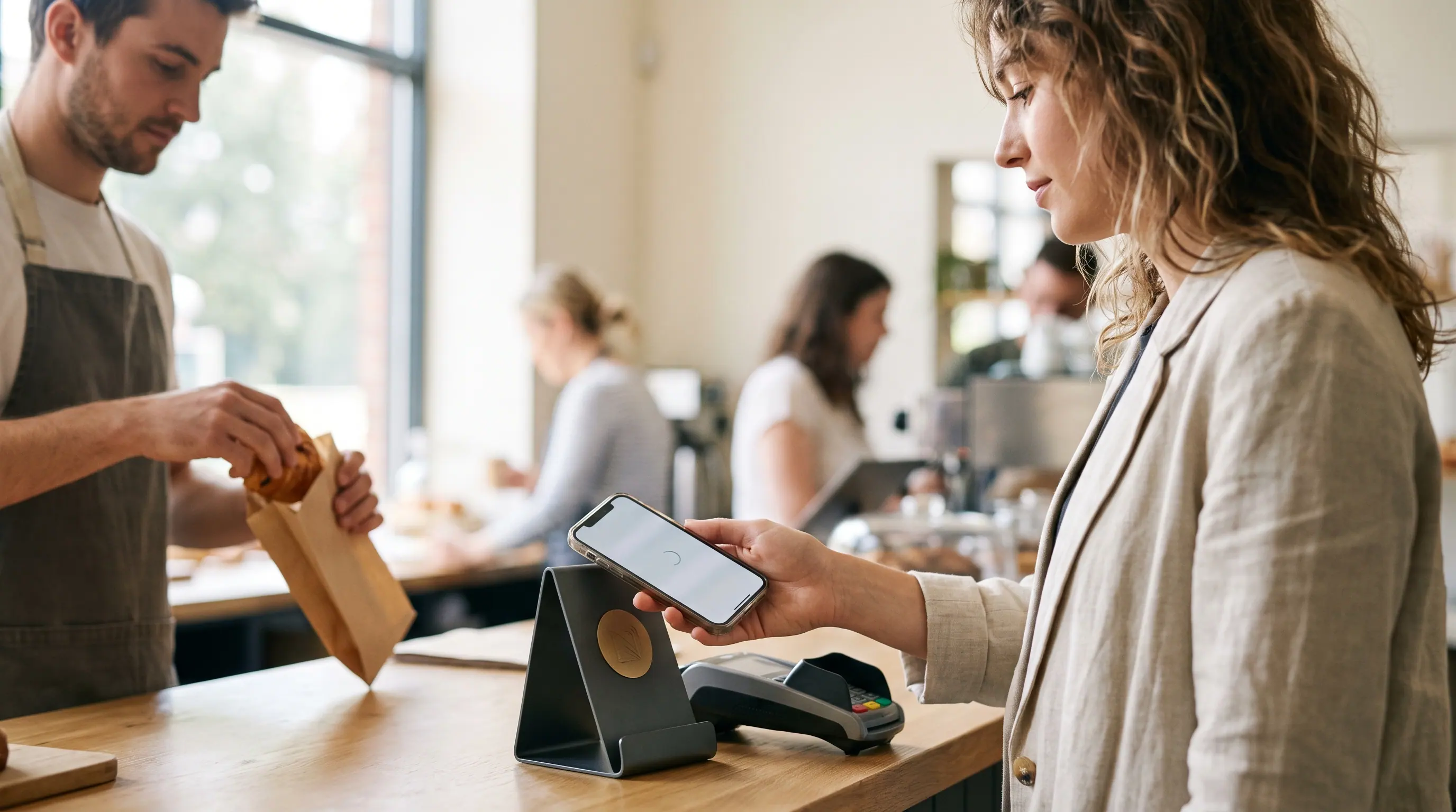 Gästin hält ihr Smartphone an einen NFC-Bewertungsaufsteller auf der Theke.